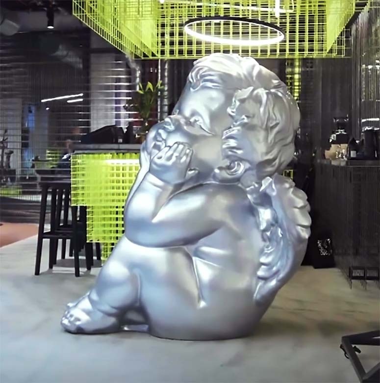 Large silver cherub sculpture with a modern finish, displayed at the Lynk & Co Club store in Hamburg