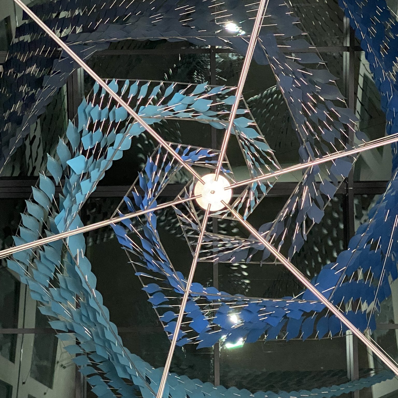 Vortex-shaped sculpture made of stainless steel and blue paper leaflets, suspended in a 9-meter-high glass atrium at Solenis sales headquarters, Mönchengladbach