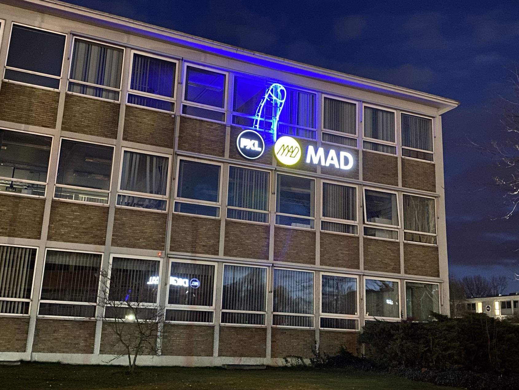 Custom neon lamp installation for artist Gunther Segers, created by Art Nzo, on the façade of PXL-MAD School of Arts at night