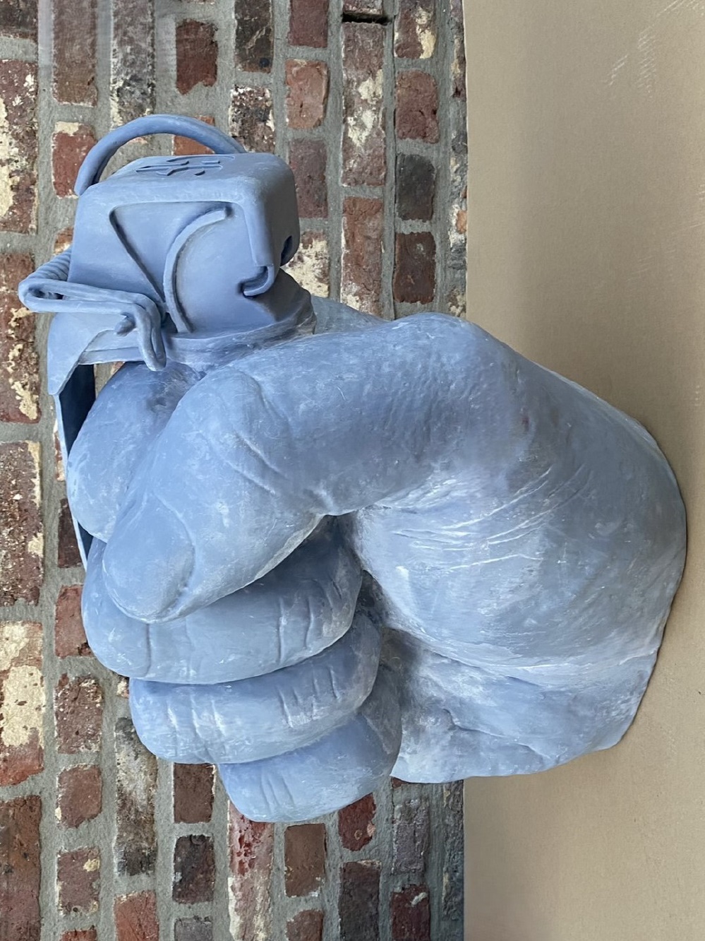 Large scanned and 3D-printed hand grenade sculpture in front of a wall, ready for finishing